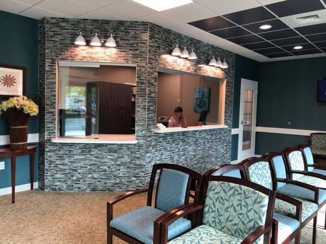 Office patient reception room with rows of chairs and stone patterned wall