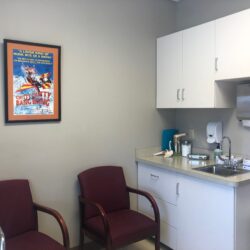 Exam room with chairs, cabinets and a sink.