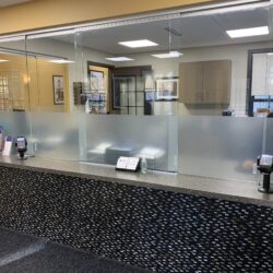 Receptionist beind long counter with glass guard