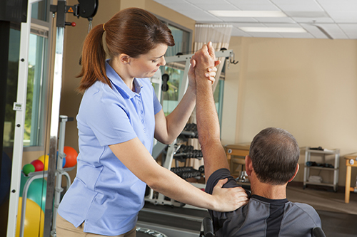 Physical Therapist Evaluating Range Of Motion Of Wheelchair Patient