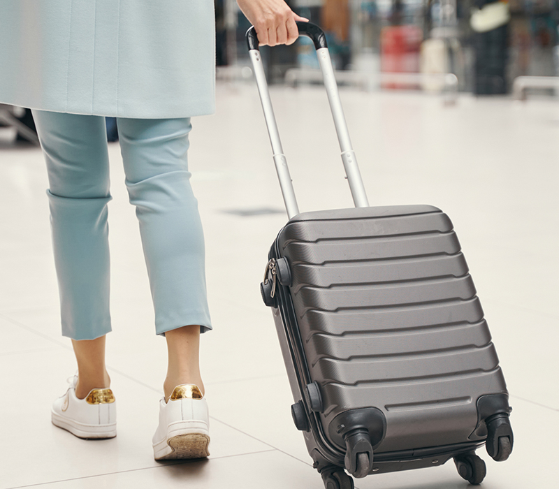 Air traveler wheeling baggage through airport terminal