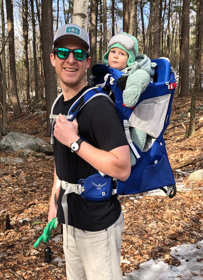 Doctor Schmidtberg hiking carrying baby on back