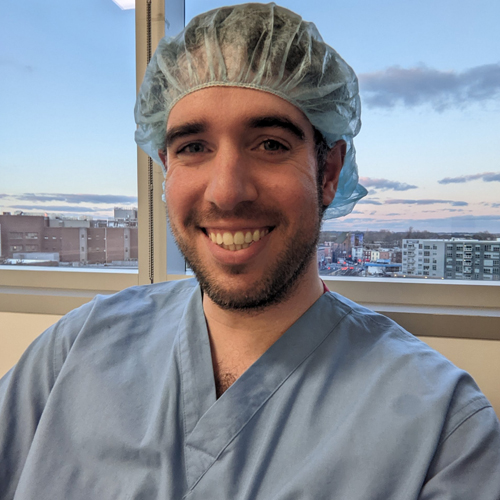 Doctor Boniello in surgical scrubs smiling in front of window
