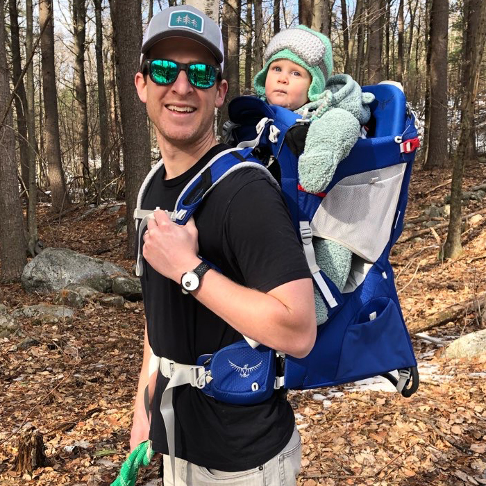 Doctor Schmidtberg hiking carrying baby on back