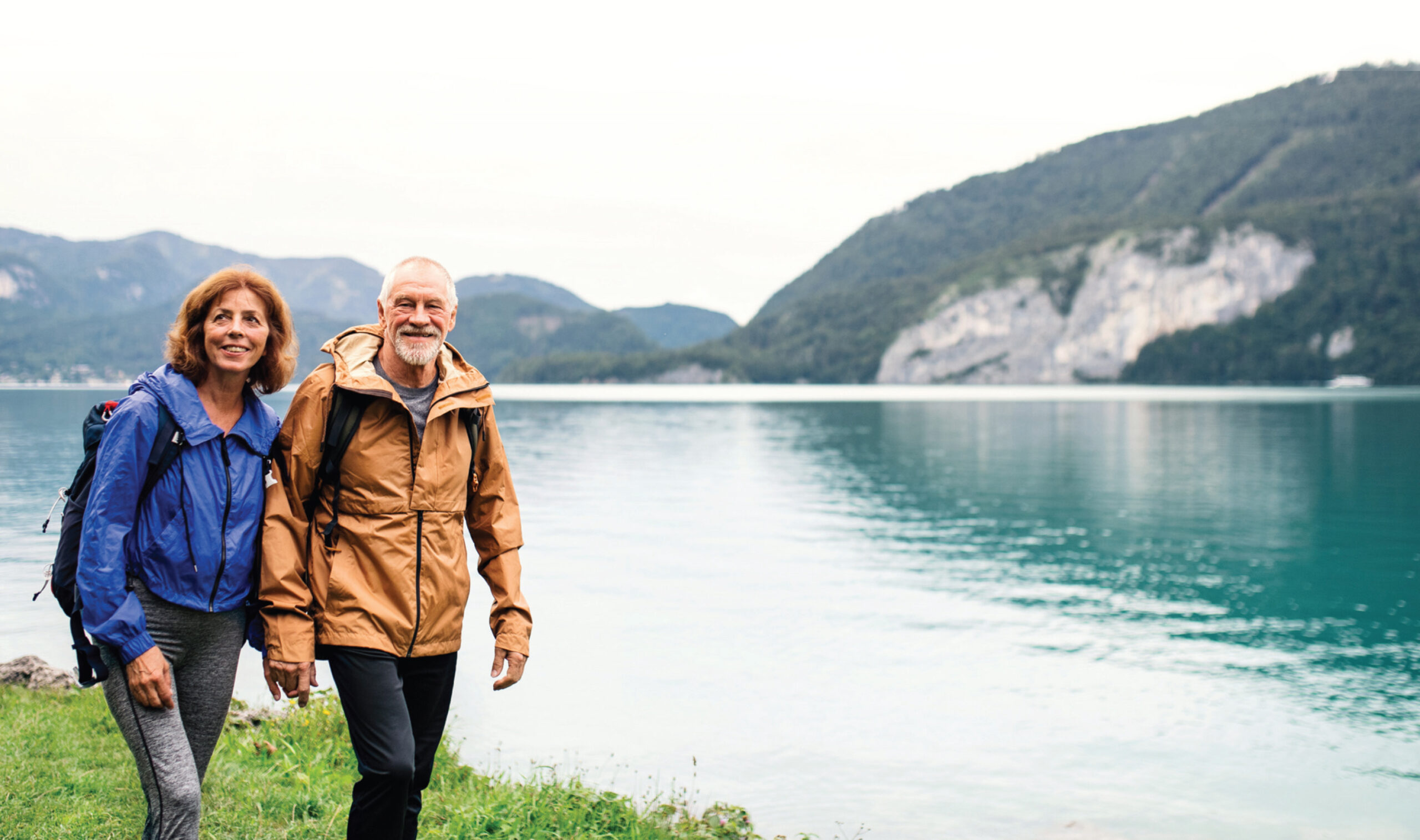 Older man and woman hiking near a lake