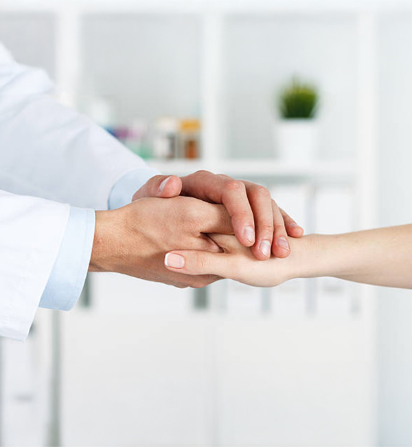 Friendly male doctor's hands holding female patient's hand for encouragement and empathy. Partnership, trust and medical ethics concept. Bad news lessening and support. Patient cheering and support